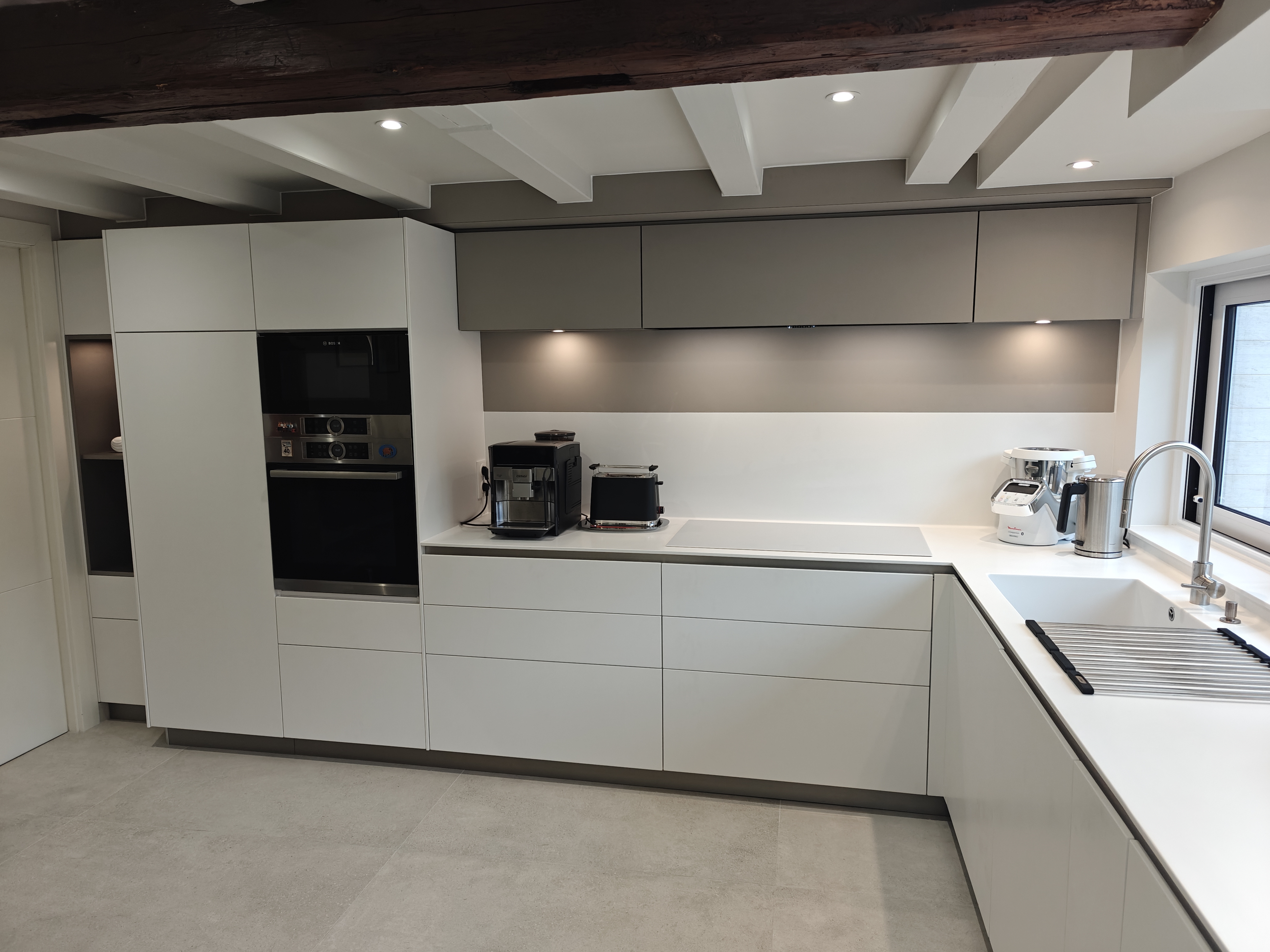 Photo d'une cuisine blanche en coin réalisée par la menuiserie Ennesser